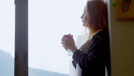 Woman-having-coffee-while-looking-through-window-4k