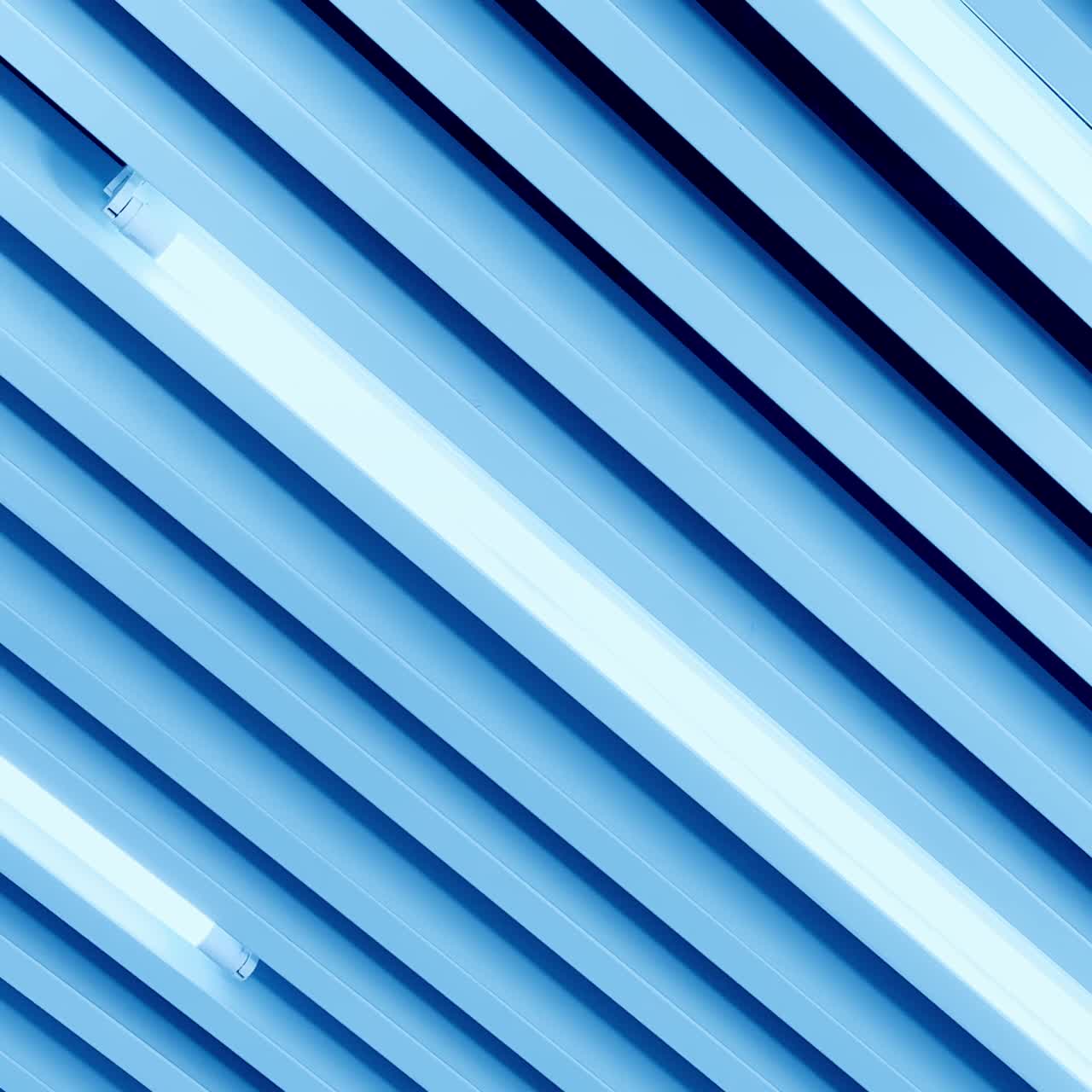 White light of long led lamps among the decorative panels on the ceiling. View from below