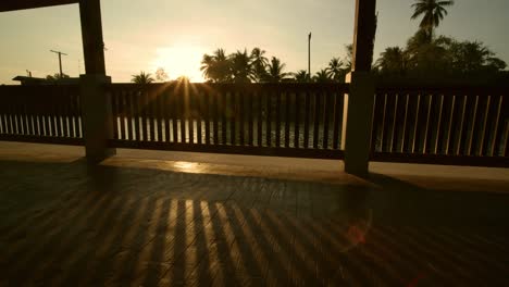 The-suns-sets-beyond-the-village,-river-and-palm-trees-in-Samutsongkram,-Thailand---static-time-lapse