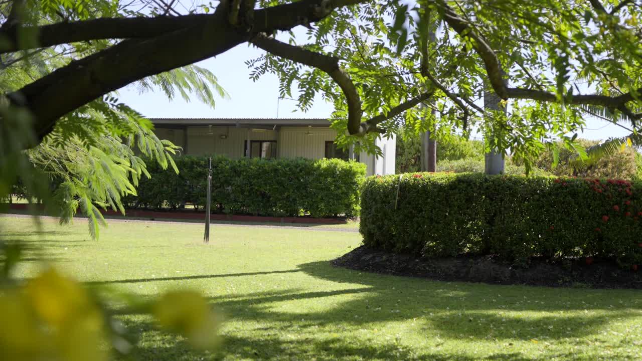 Green lawns and manicured hedges in front of a small house