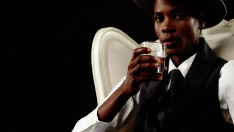 Androgynous-man-drinking-whisky-on-armchair