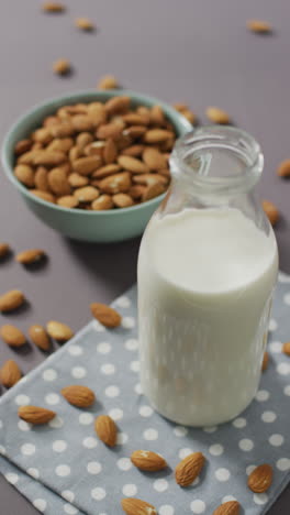 video vertical de un tazón de almendras y una botella de leche en fondo lila