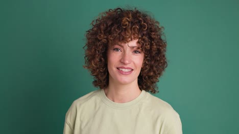 smiling standing young curly haired woman on green background