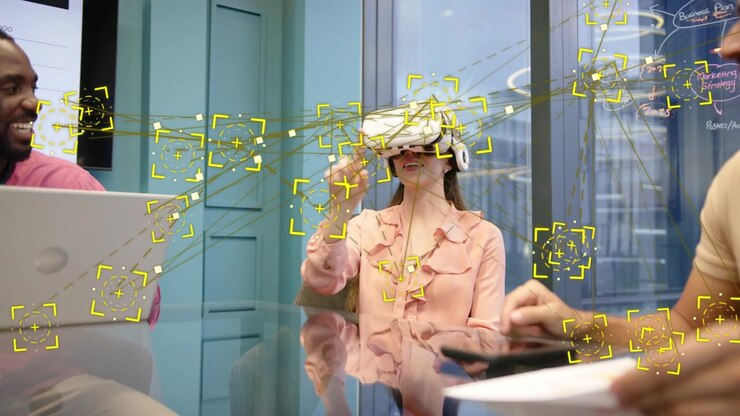 Woman with VR headset raising hand and tapping yellow markers, team using tablet during tech demo
