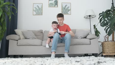 Two brothers play game with mobile smartphone at home 4K
