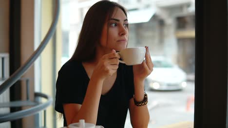 Schöne-Junge-Frau-Träumt-Mit-Einer-Tasse-Heißen-Kaffee-über-Dem-Fenster-In-Der-Kaffeeaufnahme.-Pause-Nach-Einem-Langen,-Anstrengenden-Tag.-Entspannung-Mit