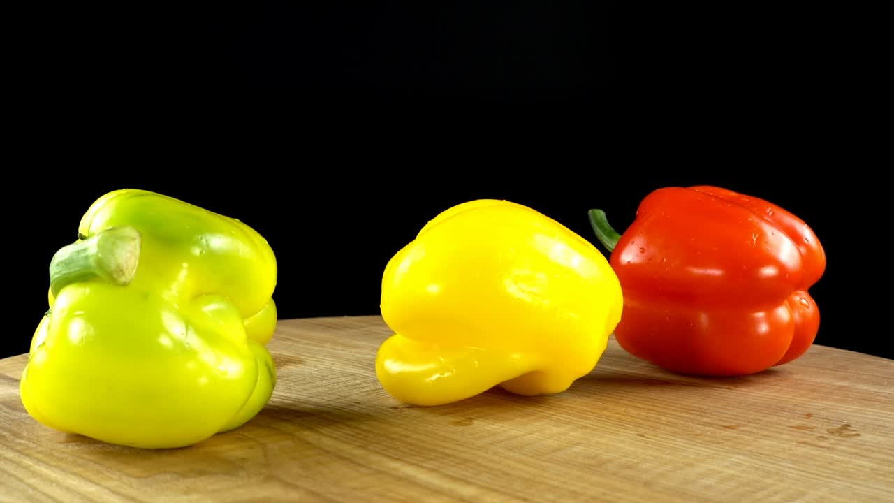 Sweet pepper on a black background. Cutting board in the movement