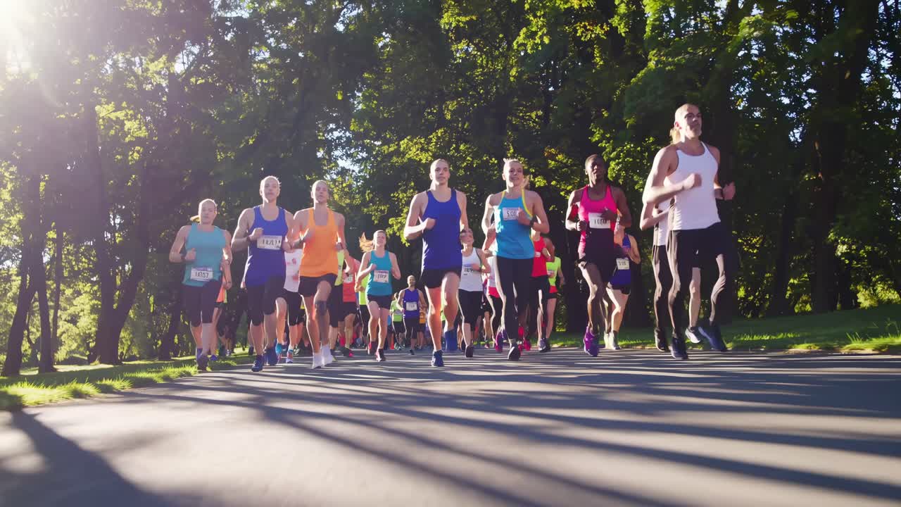 A dynamic low-angle video shot of a diverse group of runners in a park, capturing the energy