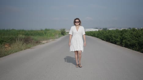 woman walking down a country road in a white dress