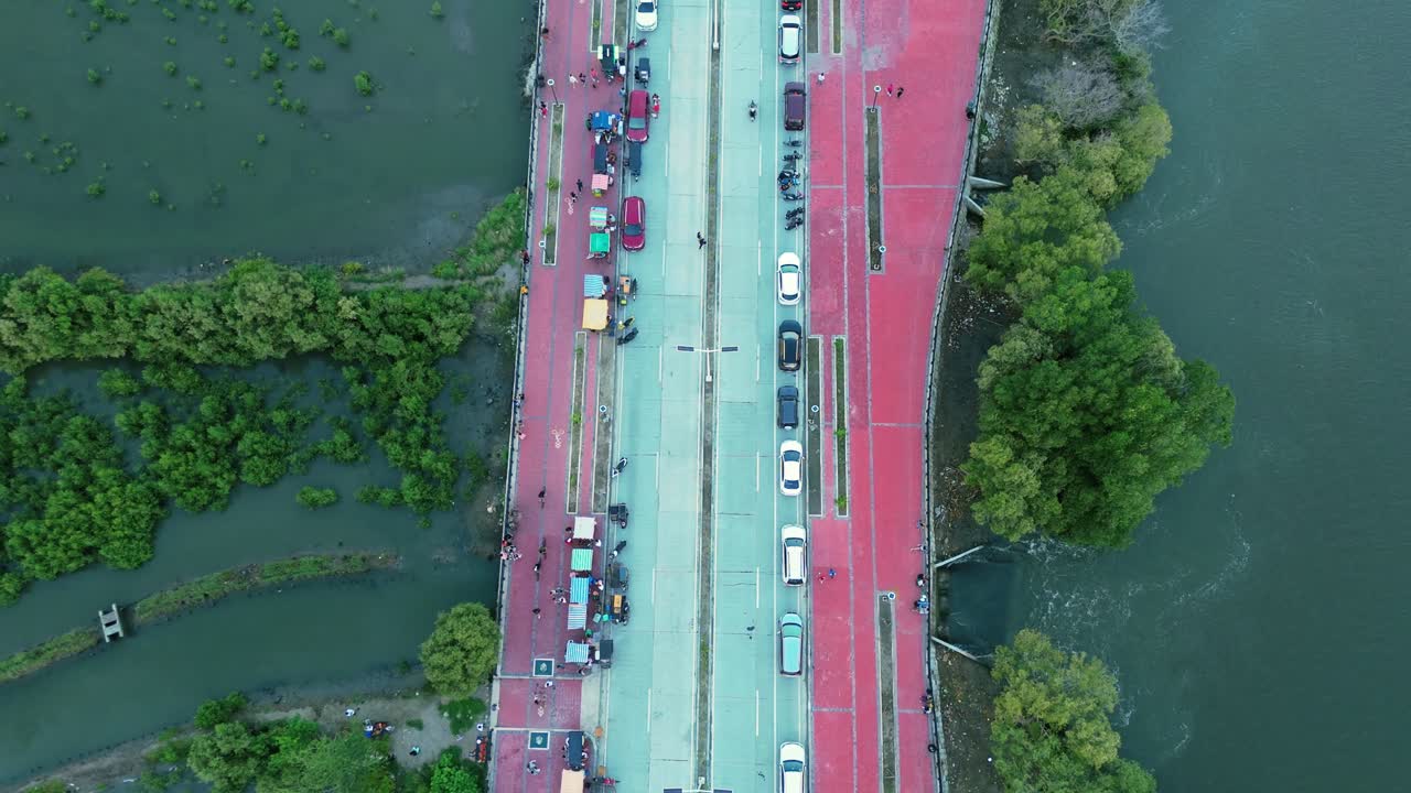 Cinematic top-down drone view of a riverside road in the Philippines with cars, food stalls, and mangroves. Perfect for travel, culture, urban planning, and lifestyle projects