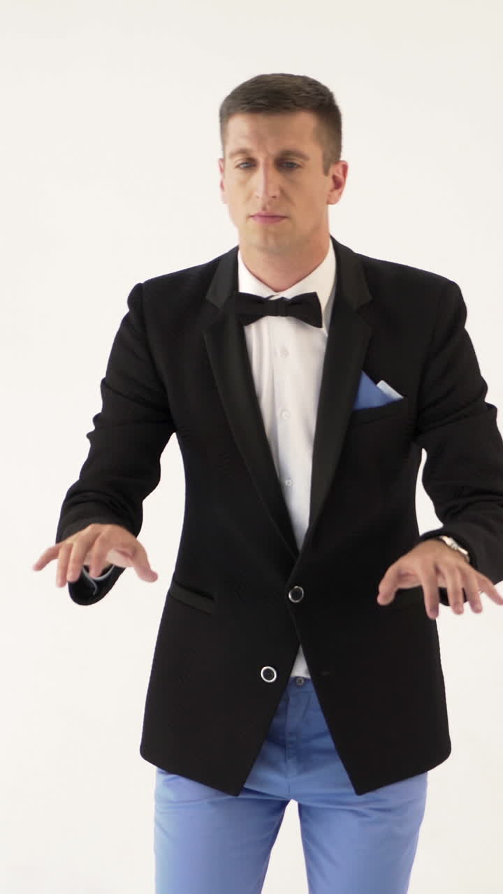 a man in a black jacket is depicting play the piano on a white background in the studio. Parody of the pianist or the instrument Vertical video