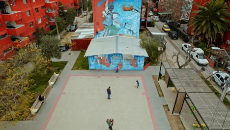 drone tilt down shot of children playing soccer with adults in the open air museum in san miguel, a reclaimed residential neighborhood. santiago de chile