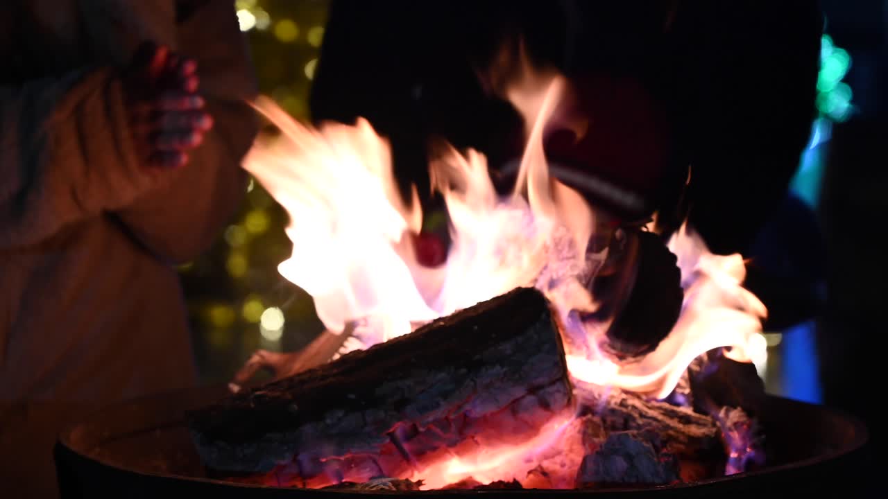 Close up of people warming their hands on a fire burning outside