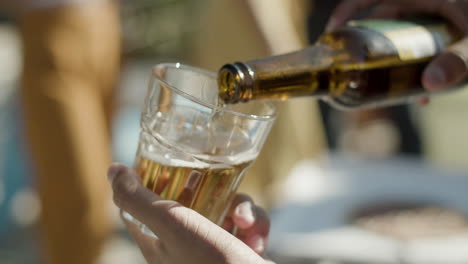 close-up shot van een onherkenbare man die glas in de hand houdt en er bier in giet