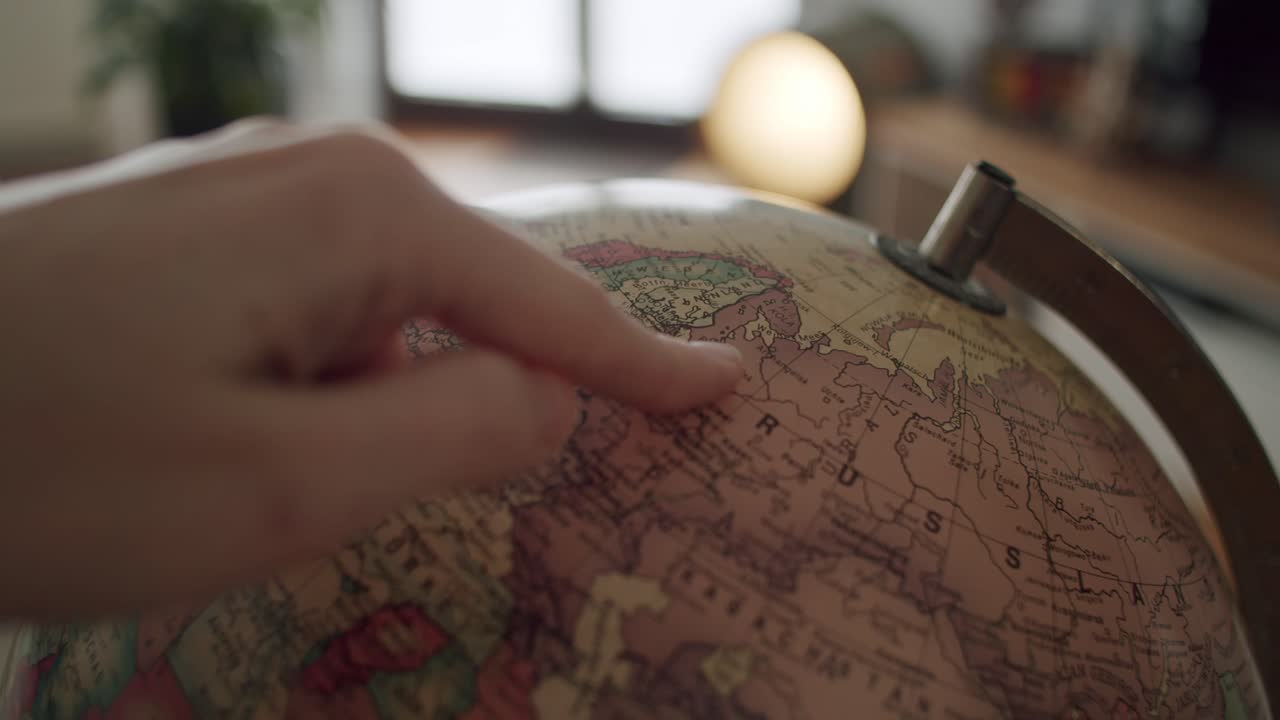 primer plano de un globo terráqueo girando hasta que una mano entra en el marco y apunta a rusia