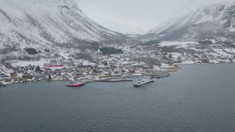 ferryboat departs olderdalen town at foot of foggy, imposing mountains