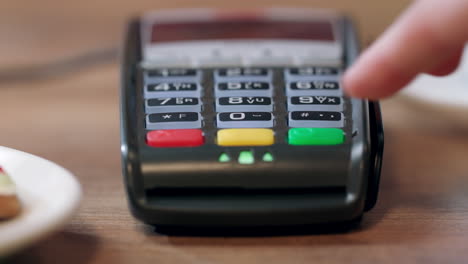 pago de terminal postal en una cafetería. la mano de la mujer ingresa el código pin en la terminal de pago.