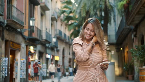 Happy-woman-wearing-headphones-outdoor.-Smiling-girl-listening-music-at-street.