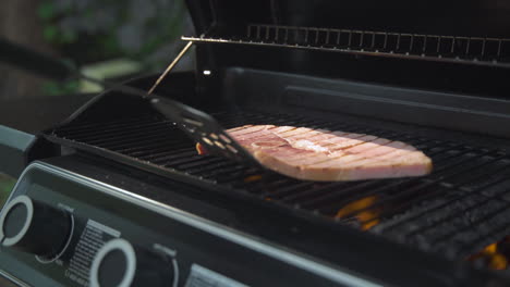 Un-Hombre-Abre-Una-Barbacoa-Y-Voltea-Un-Filete-De-Jamón