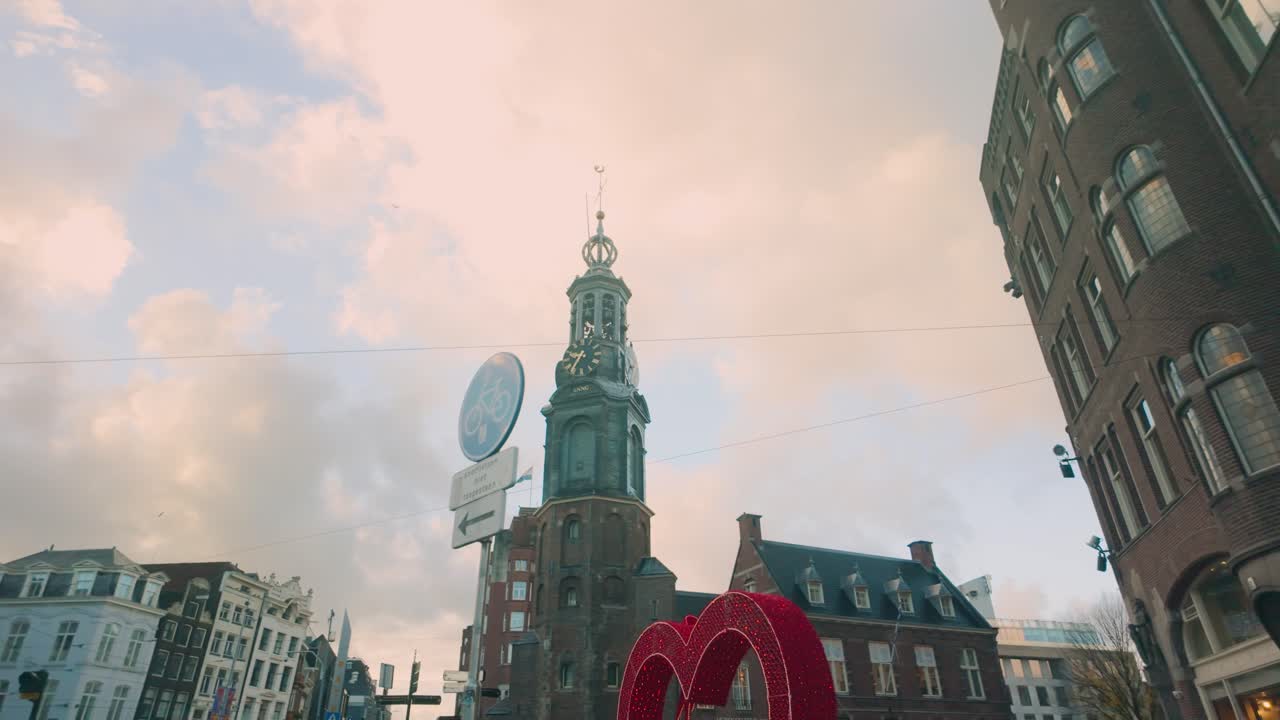 Picturesque view of Amsterdam’s skyline featuring a historic clock tower against a vibrant morning sky. The blend of historic architecture and soft pastel tones highlights the city’s timeless charm.