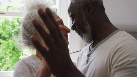 close up of mixed race senior couple dancing together in the kitchen at home