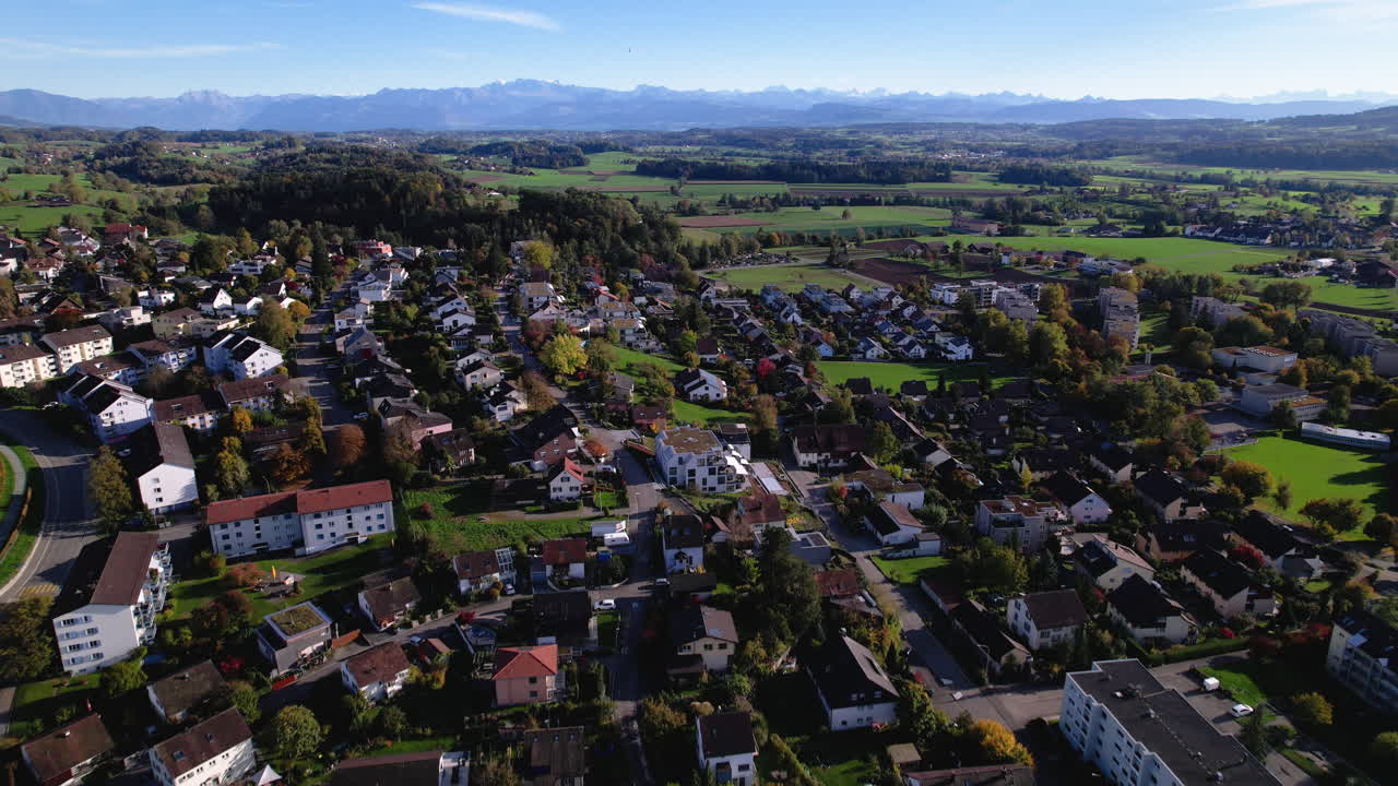 Dronefoto van een groene stad in Zwitserland met Alpen op de achtergrond