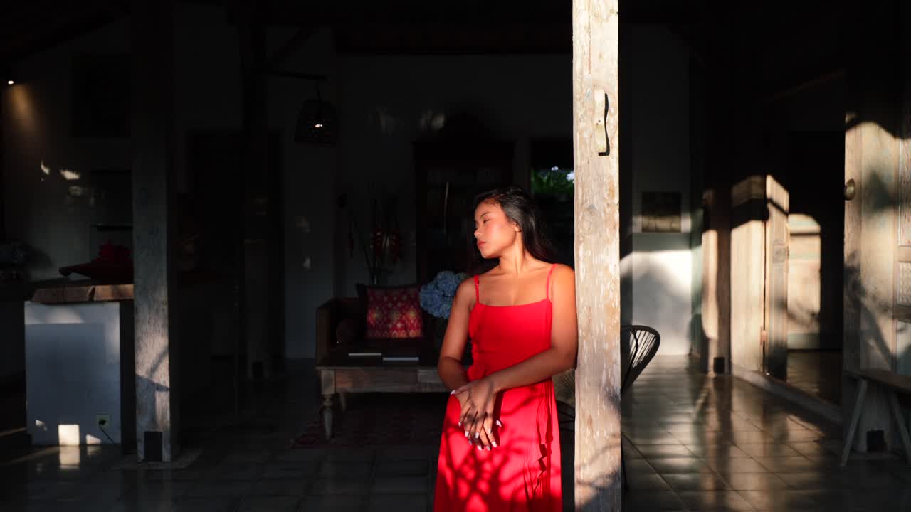 bella ragazza asiatica che posa in maxi vestito rosso alla villa di bali con il bagliore del sole all'ora d'oro