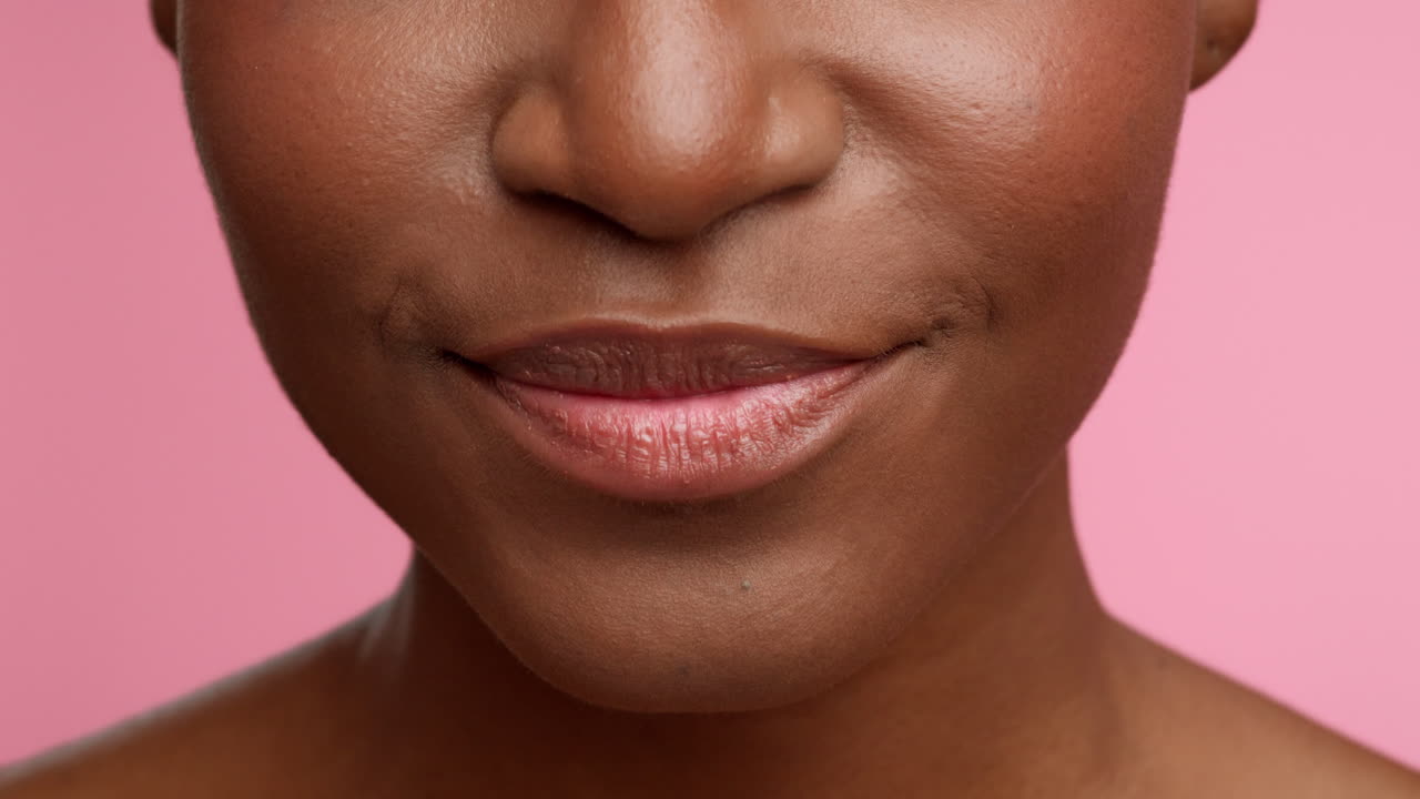 Close-up of a person's mouth with dental braces smiling on a pink background