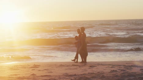 Video-Einer-Glücklichen-Afroamerikanischen-Familie,-Die-Bei-Sonnenuntergang-Am-Strand-Spaziert