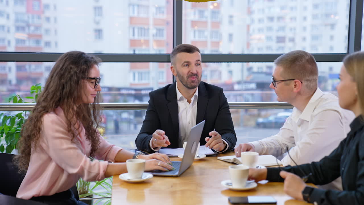 Creative team sitting at the desk communicating and laughing. Boss talks to his employees expressing thoughts and gesturing.