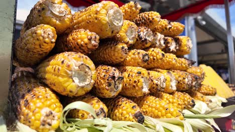 stack of roasted corn cobs at an outdoor food stall