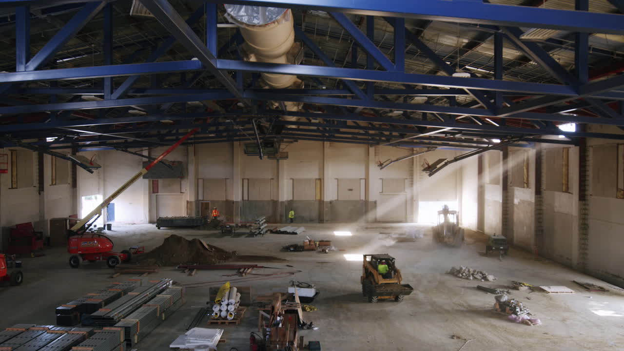 Large Industrial Building Interior Under Construction with Machinery and Workers