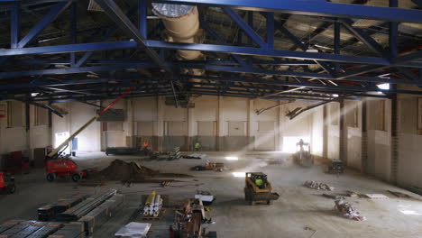 large industrial building interior under construction with machinery and workers