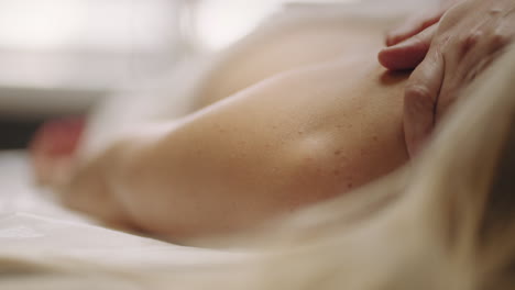 relaxing treatment in massage parlor woman is lying on massage table masseur is rubbing arms muscles of patient