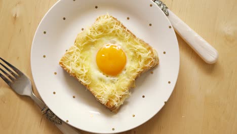 top view of toast with fried egg and cheese on wooden kitchen table