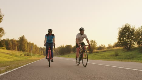 steadicam shot of mountain biking couple riding on bike trail at sunset doing high.