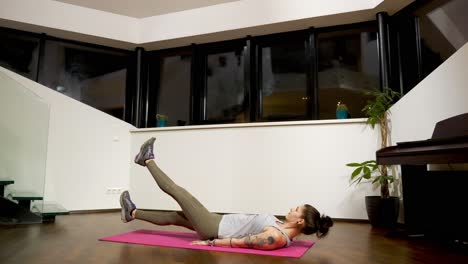 Raising her legs alternately, the woman is doing flutter kicks to strengthen her core and the muscles of her abdominal wall