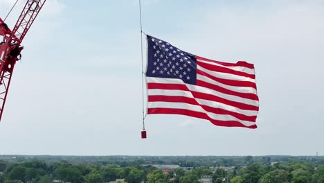 hung from a construction crane, the flag of the united states waves in the wind