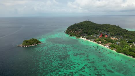 Koh-Lipe-Thailand--Aerial-fly-in-over-coral-reefs-and-long-tail-boats-anchored-along-coastline