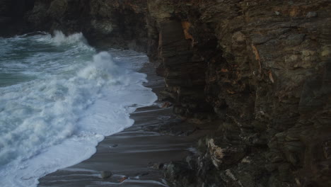 coastal cliffs with splashing waves at treveglas cove in st agnes, cornwall, uk - static shot