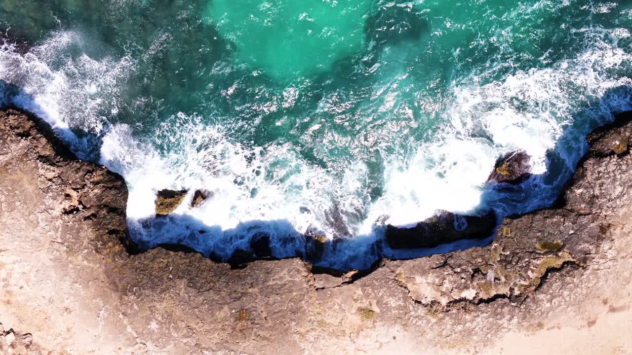 Waves hitting rocky cliff of Italy, aerial top down view
