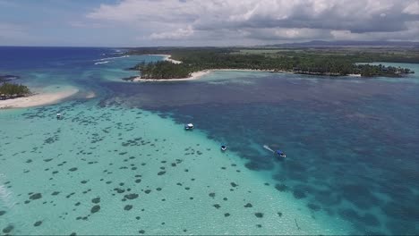 island coral reefs with a speedboat moving across the crystal clear ocean waters of the isle island in mauritius