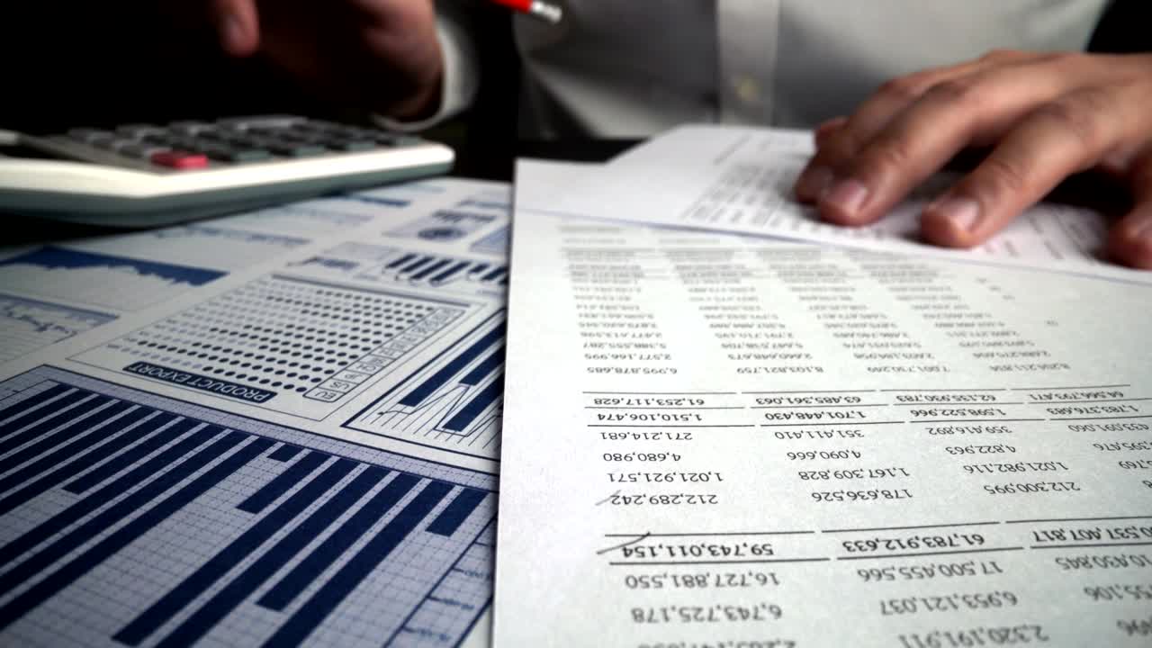 Accountant analyzing business marketing data on paper dashboard at office table.