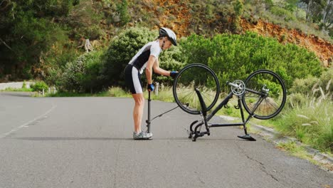 middle age athlete pumping a bicycle tire with bike pump on country road 4k