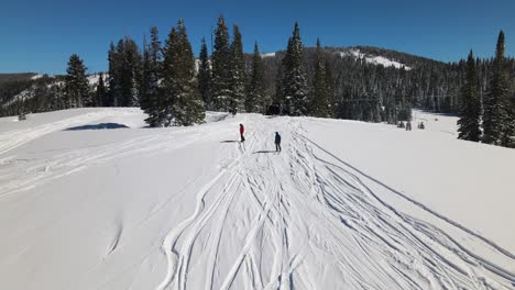 Hervorragende-Luftaufnahme-Eines-Snowboarders-Und-Skifahrers,-Die-Ihre-Abfahrt-Beginnen