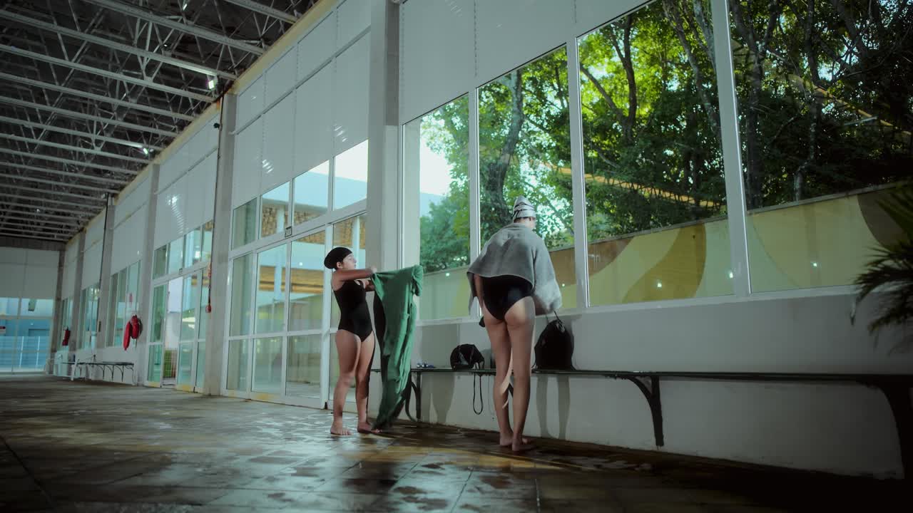 Two women drying themselves after swimming at an indoor pool