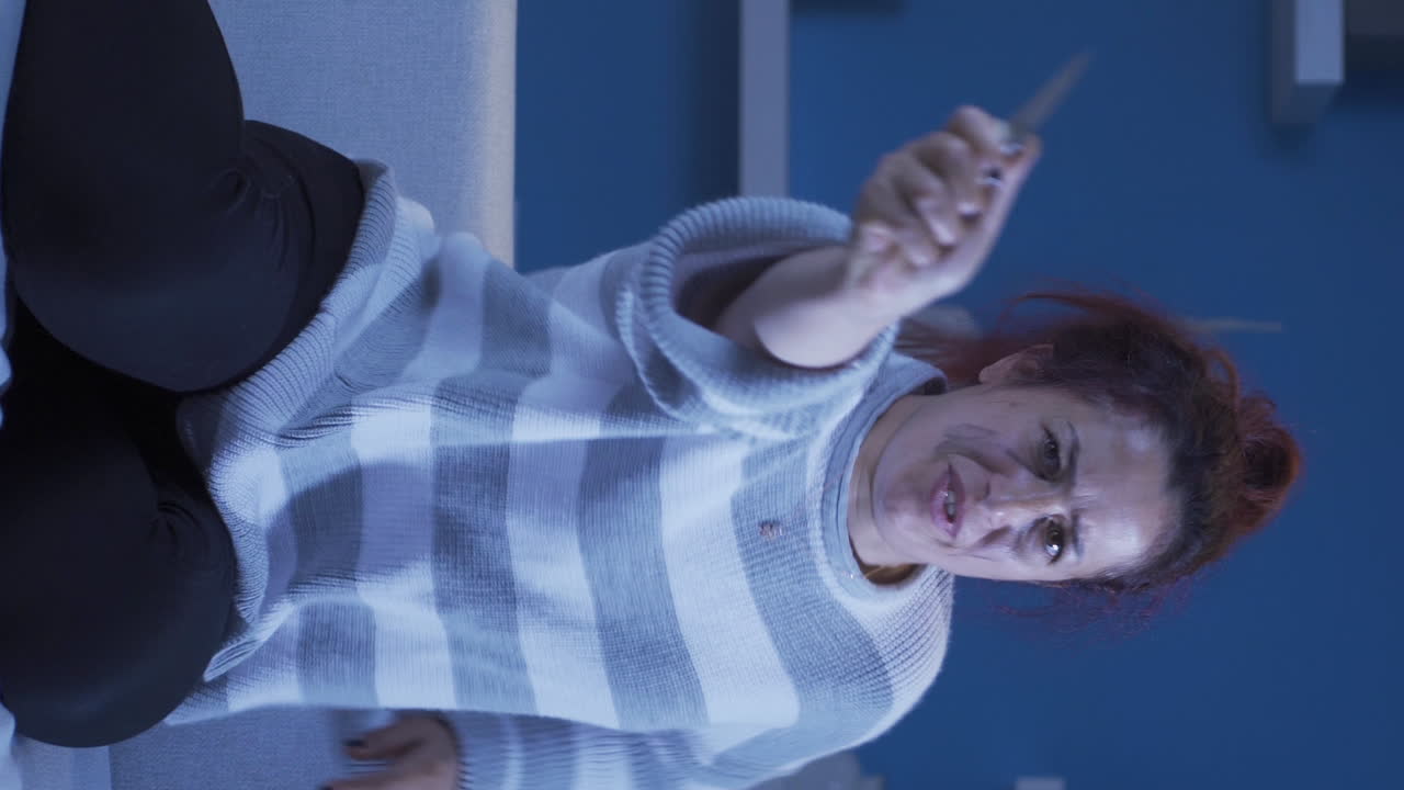 카메라에 칼을 겨누고 있는 정신나간 여성의 수직 비디오.