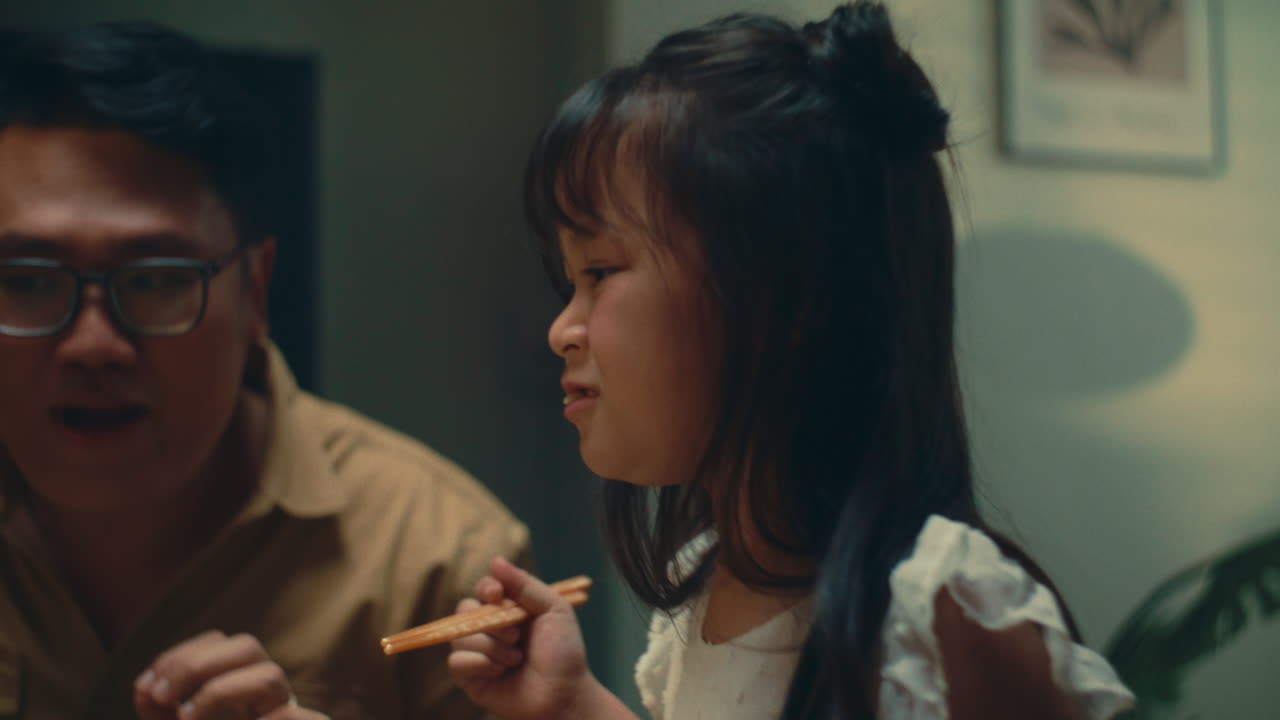 Family sharing a happy dinner, with a child enjoying the moment with her parent