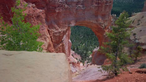 toma panorámica lenta con enfoque de bastidor desde la roca en primer plano hasta un arco hoodoo de arenisca en el fondo