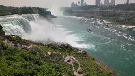 Aerial View of Niagara Falls with Observation Deck. Drone view of Niagara Falls showing powerful rushing water and mist with a riverside observation deck below